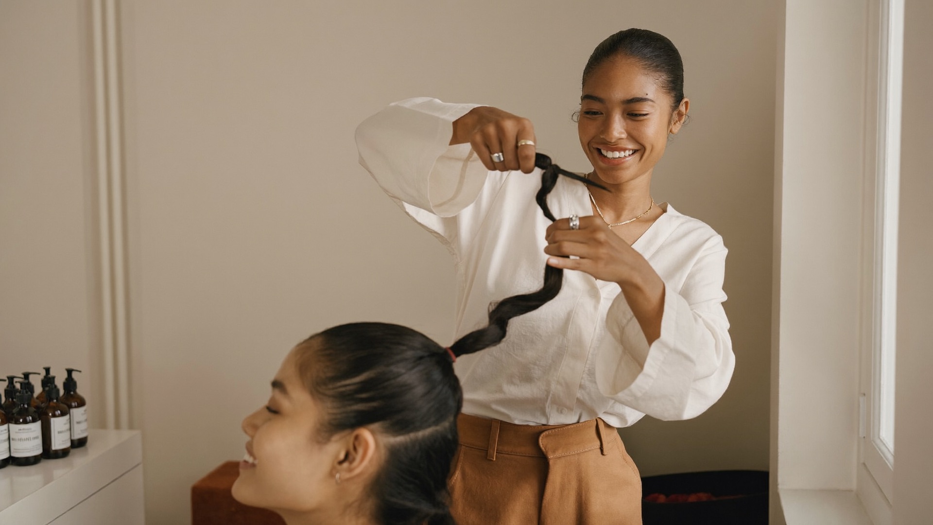 An independent braider working with a client in her sunlit home studio